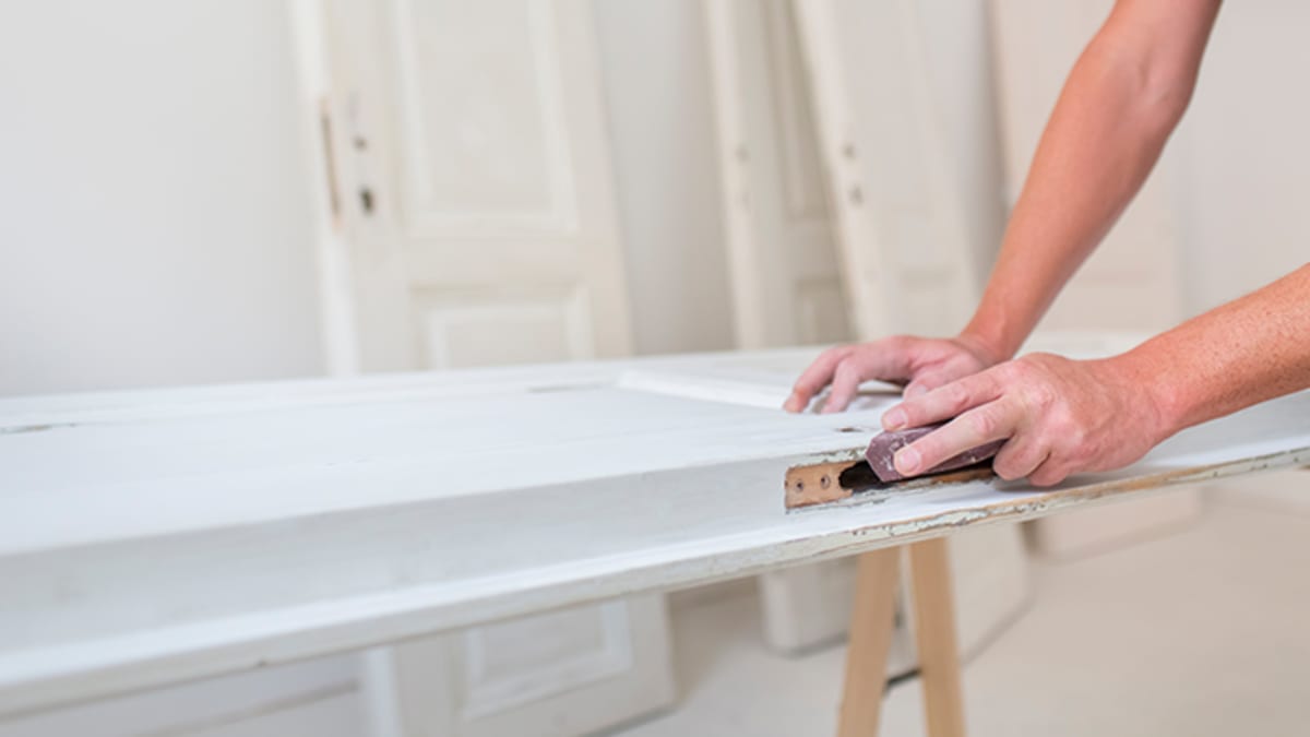 Hands preparing the surface of a white interior door