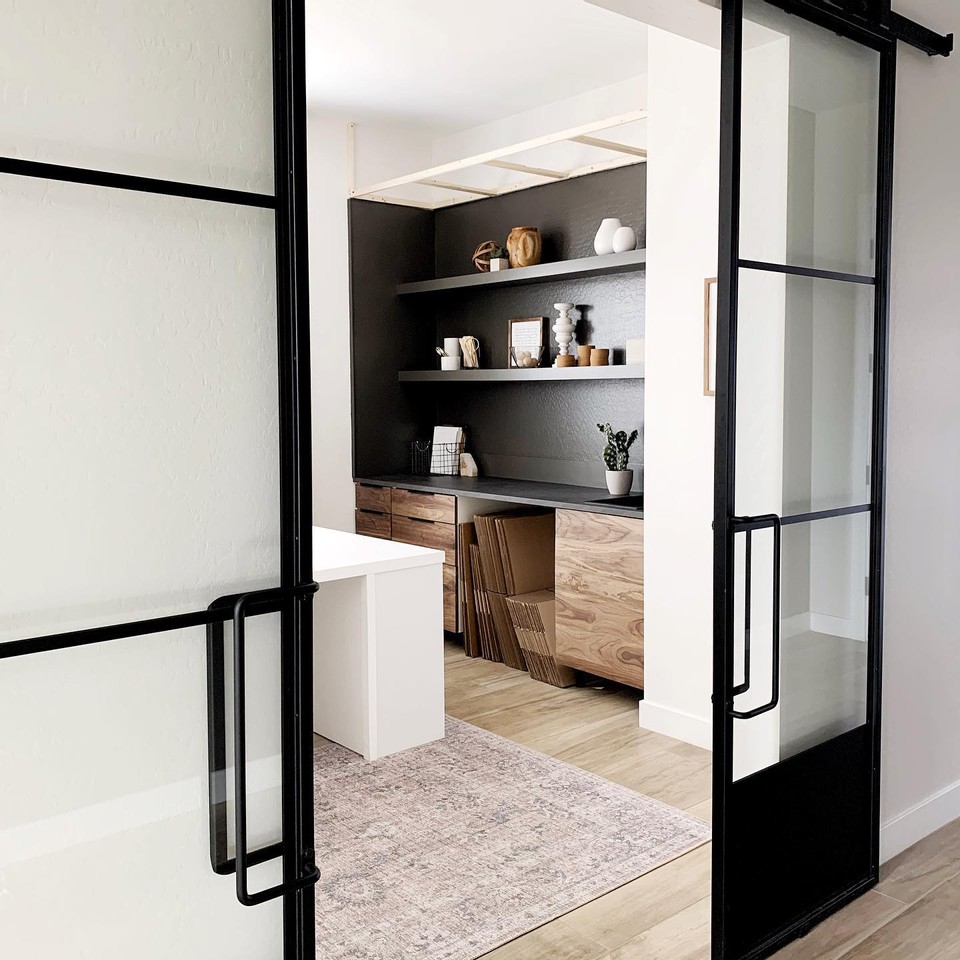 double french metal and glass barn doors opening up to an office with custom build grey shelves