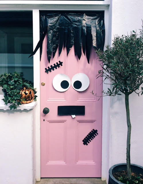 Pink front door dressed as Frankenstein with black fringe hair, paper plate eyes and stitches