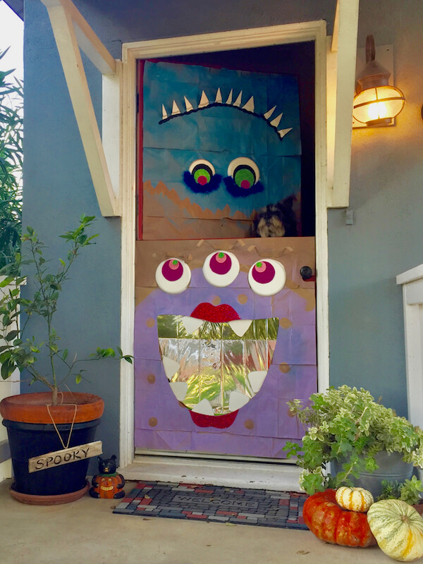 A Dutch door with the upper half open, a blue monster on top and a purple three eyed monster below
