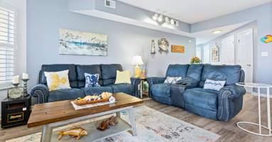 Sink into plush blue recliners in your spacious living room, where coastal artwork and warm lighting create the perfect retreat.