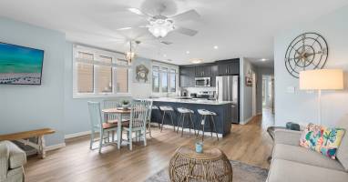 Spacious open layout with coastal charm, featuring a full kitchen, bar seating, dining table for four, and a cozy living area—perfect for relaxing and entertaining by the lake.