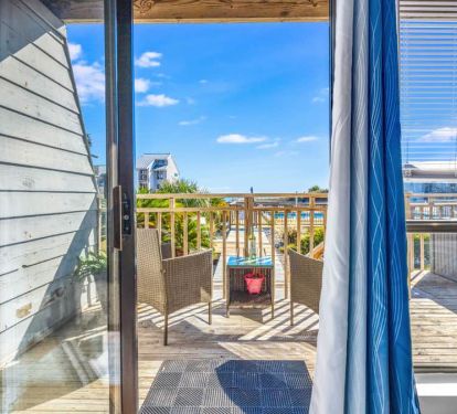 Pool-and-beach view deck with relaxing chairs, side table, and hooks for towels&mdash;easy breezy.