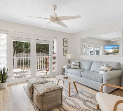 Bright and airy living room with a comfy sleeper sofa, cozy seating for all, and a ceiling fan. 