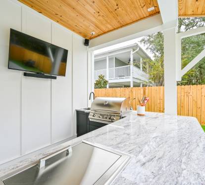 Summer Kitchen equipped with a 50" Smart TV, Surround Sound, ice box, and a Built-In Grill
