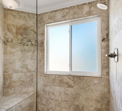 Large frameless shower with porcelain tile and river rock in master bathroom