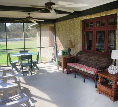 The screened-in porch with plenty of seating and a dining area