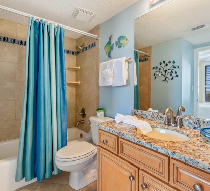 The guest bathroom has an elegant tile tub surround and large granite vanity