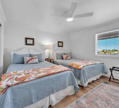 Guest bedroom with two comfortable queen beds, flat screen tv and ceiling fan