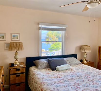 Master bedroom with view of bay, king size bed &amp; small TV with streaming services.