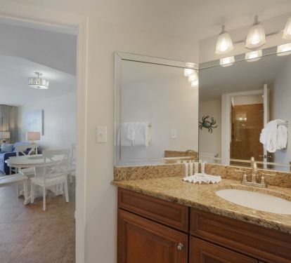 Spacious half bathroom off kitchen  with elegant granite vanity and large mirror, offering comfort and convenience during your Emerald Coast stay.