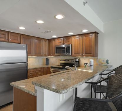 Fully equipped kitchen with modern appliances, bar seating, and ample counter space for preparing meals after a day on the beach.