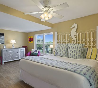This bright beach-themed master bedroom offers comfortable furnishings, a flat-screen TV, and plenty of space to unwind during your Gulf-front getaway.