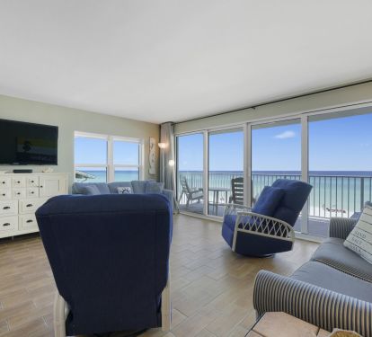 Open-concept beachfront condo living area with large TV, ocean views, and private balcony seating