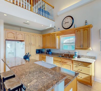 The classic, fully equipped kitchen boasts high-quality appliances, sleek countertops, and a breakfast bar with seating for three.