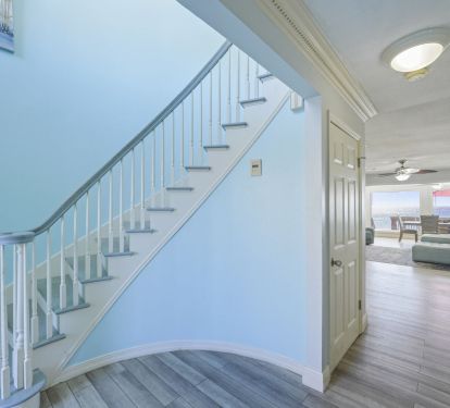 Natural light pours through the windows along this coastal staircase, offering a warm and inviting first impression of life at Captains Quarters in Destin.