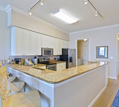 Coastal-style kitchen with granite bar and stainless steel refrigerator
