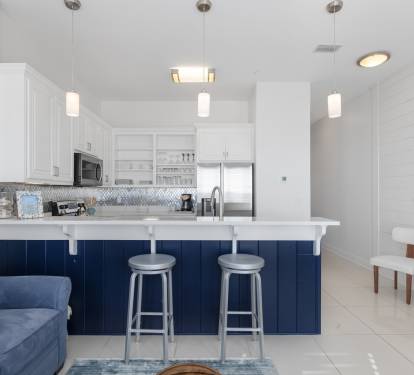 Your sleek kitchen features navy blue island seating, modern pendant lighting, and stainless steel appliances for effortless meal prep.