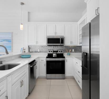 Your modern kitchen awaits with gleaming countertops, stainless appliances, and ocean artwork that sets a coastal mood for preparing meals.