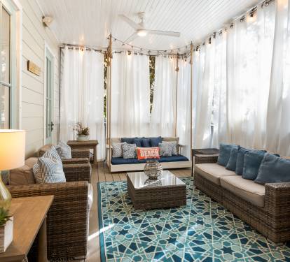 Unwind in your private screened porch with plush seating and flowing curtains that create the perfect coastal retreat for morning coffee or evening relaxation.
