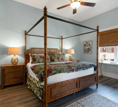 Relax in your elegant four-poster bed beneath a gentle ceiling fan, with soft morning light filtering through bamboo blinds.