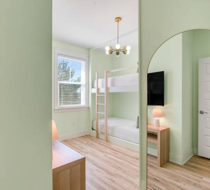 Your kids will love this cheerful bunk room with soft green walls, cozy lighting, and space to play and rest.