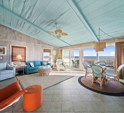 Relax in this stunning oceanfront living space where turquoise ceilings and vibrant furnishings create your perfect coastal retreat.