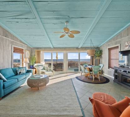 Relax in your bright coastal living room with ocean views, turquoise sofa, and modern kitchen—your perfect beachfront retreat awaits.