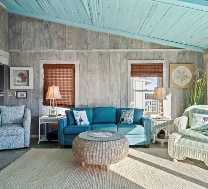 Relax in this coastal living room with turquoise ceiling, ocean-blue sofa, and wicker furnishings that perfectly capture beachside charm.