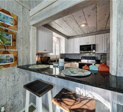 Your coastal-inspired kitchen features granite counters, modern appliances, and charming breakfast bar seating perfect for morning coffee.