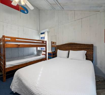 Cozy coastal bedroom with queen bed and bunk beds, perfect for families seeking comfort and fun.