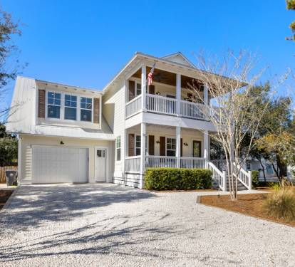 Charming coastal home with welcoming covered porches and convenient garage parking in a peaceful neighborhood setting.
