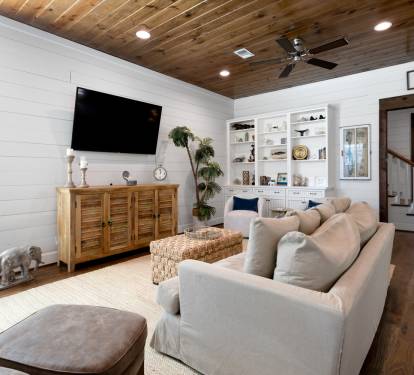 Sink into the plush sectional sofa and enjoy movie nights on the large TV in this stylish living room with rustic wood ceiling.
