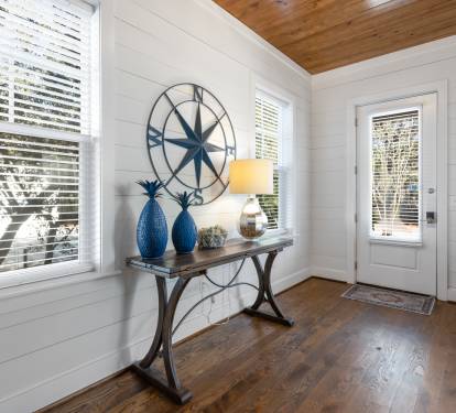 Step into your charming coastal-inspired entryway, where natural light streams through custom blinds and warm wood floors welcome you home.