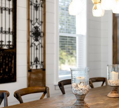 You'll love gathering around this rustic dining table, where candlelit evenings feel magical under warm pendant lighting and elegant ironwork details.