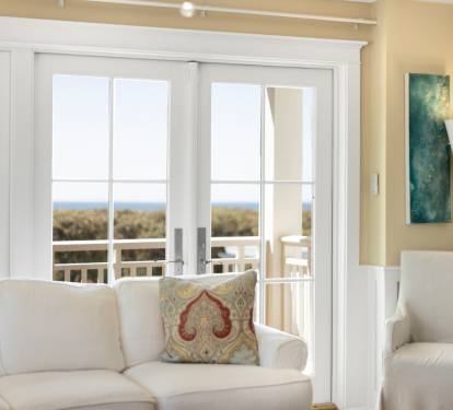 Unwind in your bright, airy living space where French doors open to reveal stunning ocean views and comfortable seating awaits.