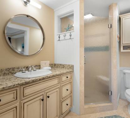 Step into your elegantly appointed bathroom featuring a spacious walk-in shower, granite vanity, and coastal touches that make getting ready feel like a spa retreat.