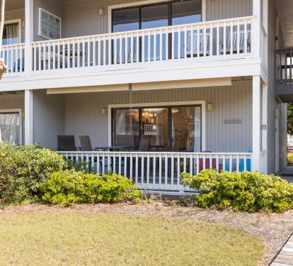 Property building with multi-level balconies and landscaped grounds featuring mature trees and manicured shrubs.