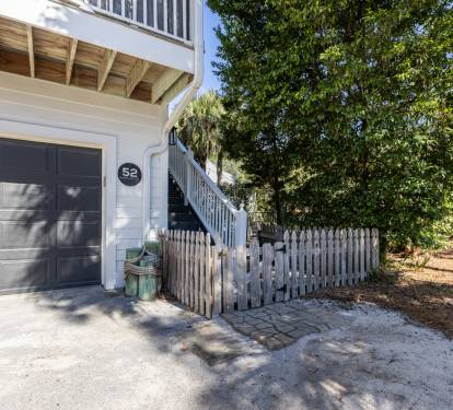 Charming coastal property entrance with convenient garage parking and natural landscaping in a peaceful residential setting.