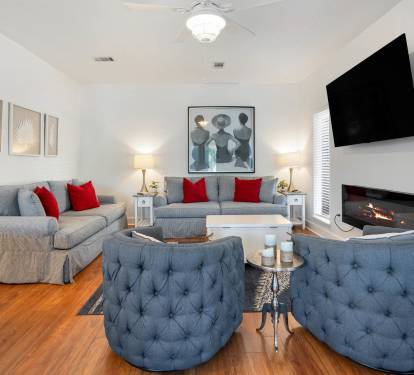 Sink into plush gray sofas with vibrant red pillows while the fireplace crackles nearby and your favorite show plays overhead.