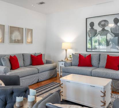 Settle into your stylish living room with plush gray sofas and bright red pillows. Natural light streams in as you relax in this thoughtfully designed space.