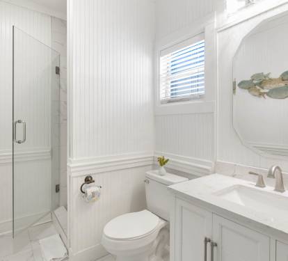Unwind in your pristine bathroom featuring elegant white marble, a spacious walk-in shower, and charming coastal touches that create a spa-like retreat.