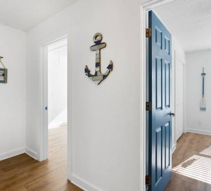 Step into your coastal haven where nautical charm meets modern comfort—sun-dappled floors and cheerful blue accents create the perfect seaside escape.