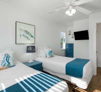 Your coastal-themed bedroom with twin beds, ocean artwork, and ceiling fan creates a refreshing retreat after beach adventures.