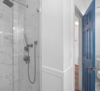 Step into your pristine marble bathroom featuring a luxurious rainfall shower and elegant blue door detail for a spa-like retreat.
