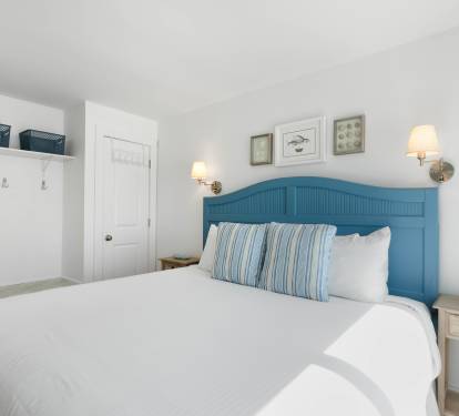 Your cozy bedroom features crisp white linens, coastal blue accents, and warm bedside lighting for peaceful nights.
