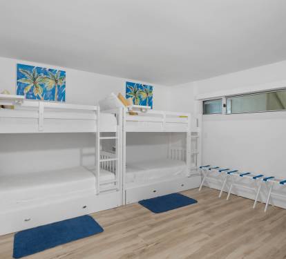 Your family will love this cheerful bunk room with crisp white beds, tropical artwork, and plenty of space for luggage storage.