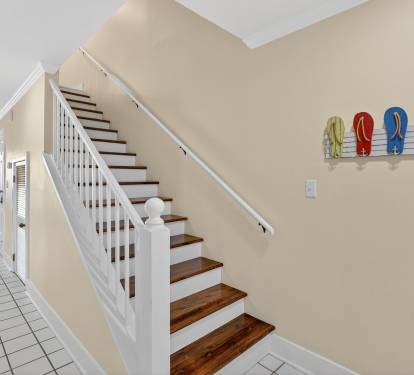 Welcoming interior staircase with coastal charm - colorful flip-flops displayed on the wall add a playful beach house touch to your stay.