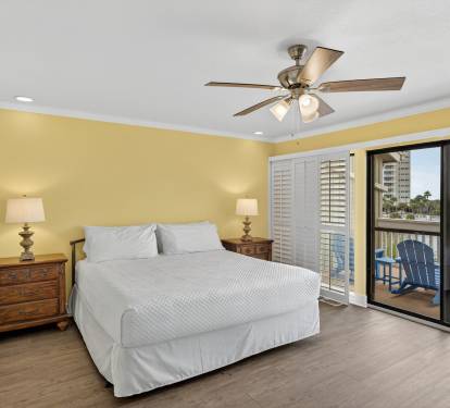 Unwind in your bright, cheerful bedroom with comfortable bedding, ceiling fan for gentle breezes, and sliding doors opening to your private balcony.