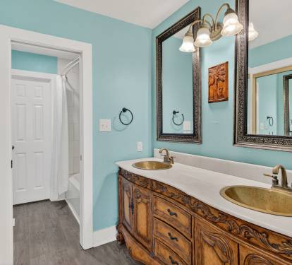Your elegant bathroom features dual vanity sinks with ornate wooden cabinetry and soothing turquoise walls for a refreshing start to your day.